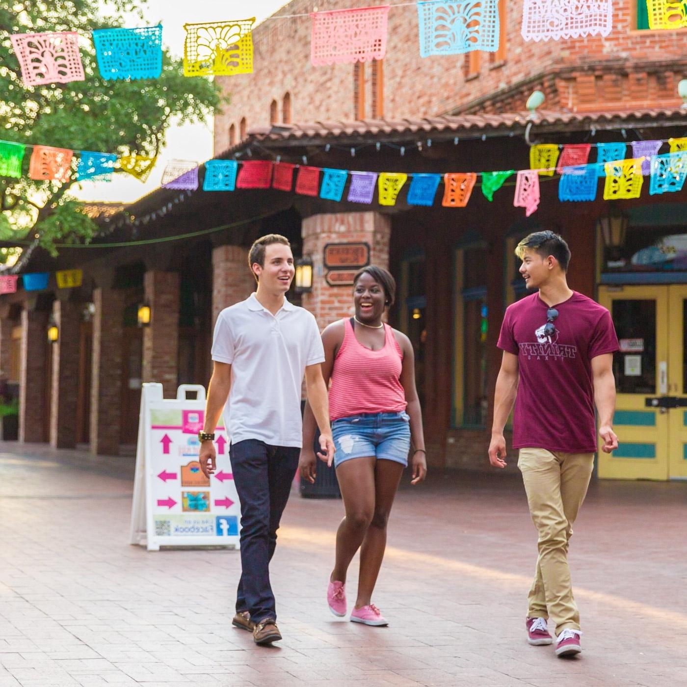 three 澳门金沙线上赌博官网 students walk through Market Square under papel picado