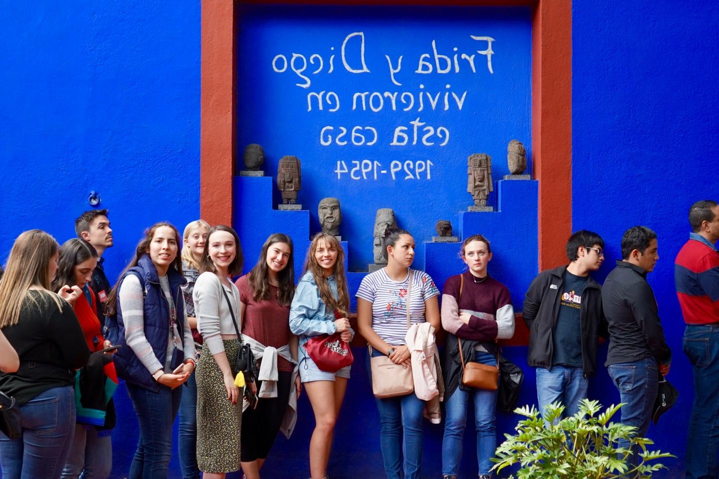 一排澳门金沙线上赌博官网的学生站在一面写着西班牙文的蓝色墙壁前